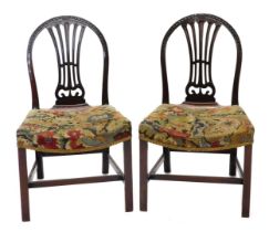 A pair of George III mahogany dining chairs, each with a hoop back carved with bell flowers, patera