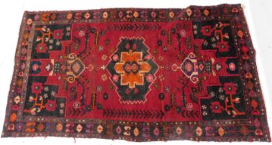 A Persian type rug, with a design of flowers, geometric devices, tendrils, etc, on a red ground with