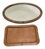 A late Arts and Crafts hammered copper oval wall mirror, with bevelled plate, decorated with roundel