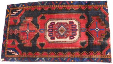 A Persian style rug, with a central medallion in red on a dark navy ground, 240cm x 135cm.