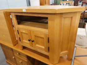 An oak corner television stand, with twin cupboard door and shelf.