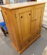 A pine storage cupboard, with two cupboard doors and single drawer, on block base.