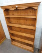 A pine bookshelf, with arched top and five shelf design.