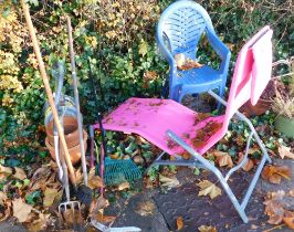 A small group of tools, terracotta planters, hose pipe and reel, pink garden lounger, two garden cha