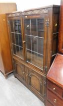 An oak two door display cabinet, with carved top rail above arrangement of two glazed doors and two