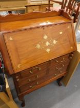 An eastern inspired walnut bureau, with a moulded back rail and inset metal design of rose gold and