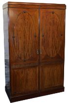 An early 20thC mahogany double wardrobe, the pediment over a pair of doors opening to reveal hanging