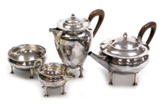 An Arts and Crafts silver four piece tea service, of compressed circular form, with lightly hammered