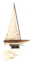 An early 20thC wooden scale model pond yacht, with rigging and sales, raised on a wooden stand, 91cm