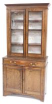 A Victorian oak cupboard bookcase, the outswept pediment over a pair of glazed doors enclosing three