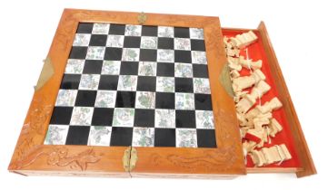 A Chinese carved boxed chess set, of hinged form, opening to reveal a chess board top, with two side