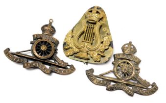 Two Royal Artillery cap badges, together with an army bandsman's cap badge. (3)