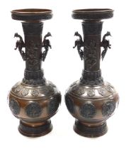 A pair of Qing dynasty bronze vases, of baluster form with twin phoenix cast handles, decorated to t