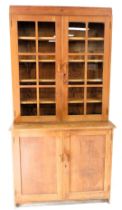 An Esavian (ESA) oak cupboard bookcase, with a pediment over two glazed doors, enclosing four shelve