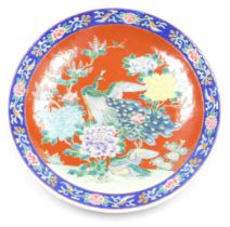 An early 20thC Japanese porcelain charger, decorated centrally with peacocks and flowers, on an oran