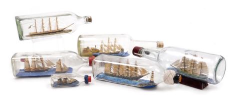 Six ships in bottles, including clipper ships, two with stands.