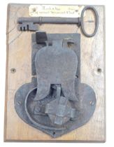 A 17thC cast iron lock and key, purportedly from a chest, oak backed.