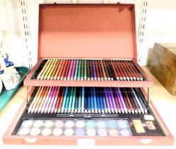 A stationery box containing coloured pencils and watercolours.