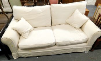 A two seater sofa, upholstered in cream fabric.