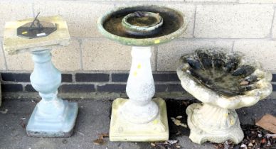 A sundial, with stone base, a birdbath with a stone base, and another birdbath in the form of a shel