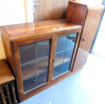 A display cabinet, with two glazed doors, and a cupboard door to right hand side, raised on a plinth