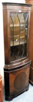 A mahogany corner cabinet, glazed door to top, panelled door below, raised on bracket feet.