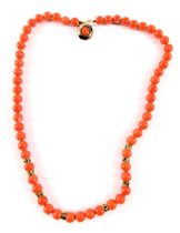 A coral type necklace, with spherical beads and gold marked breaks, with a white metal clasp stamped