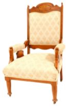 An Edwardian walnut salon chair, with an arched and carved back, and upholstered in beige with crest