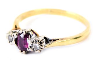 An 18ct gold ruby and diamond three stone dress ring, with central oval ruby in eight claw setting,