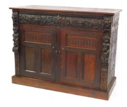 A Victorian carved oak bookcase base cupboard, fitted with two drawers and enclosed by two panelled