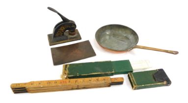 An early 20thC brass handled copper frying pan, cast iron company stamp, slide rules, a measuring st