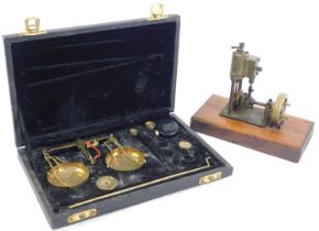 A set of gold scales, with weights, cased, together with a brass model of a pump engine on a wooden