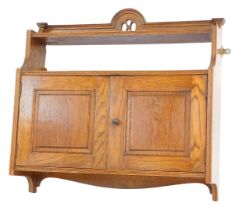 An Edwardian oak smoker's cabinet, with an arched and pierced top above two shelves with two cupboar