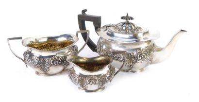 An Edward VII silver three piece tea set, of lobed form, embossed with flowers, foliate and rococo s