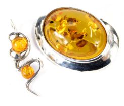 An amber set oval brooch, in white metal, stamped 925, and an amber set pendant, in white metal stam