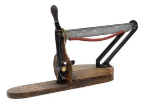 An early 20thC bread cutter, with mottled wooden base and steel blade, 81cm wide, 28cm deep.