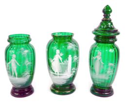 A pair of Mary Gregory style green glass jars, one with a cover, decorated with a boy and girl in a