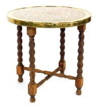 A Middle Eastern brass topped occasional table, with Arabic style design, on beech folding stand wit