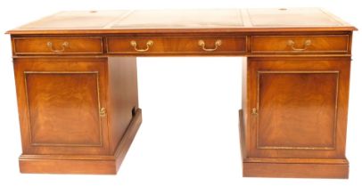 A reproduction Georgian style mahogany kneehole desk, with triple panelled green leather inset top a