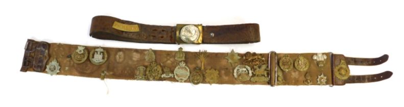 A canvas and leather belt containing various cap badges, to include Hampshire Regiment, Prince Alber