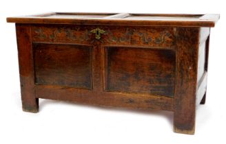 A late 17thC oak coffer, with a two panelled lid above a carved floral frieze, with panelled front a