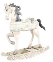 An Arabian style wooden rocking horse, with over-painted cream decoration, and a green lined saddle,