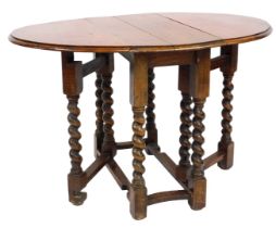 A 1920s oak oval gate leg table, on barley twist supports, 63cm high, 71cm wide, 34cm deep.