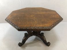 Octagonal carved oak table on tripod legs with heavily carved gothic inspired detailing including