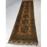 Woollen rug/runner with all over design and orange/brown ground, approx 3 metres x 76cm