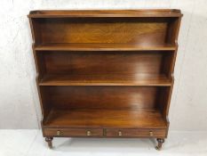 Waterfall mahogany book case with two drawers on raised turned feet with castors with makers badge