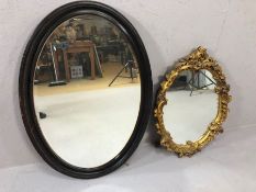 Two oval mirrors, one bevel edged in ebonised frame, the other with gold gilt decoration