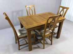 Modern oak dining table accompanied by four matching oak dining chairs with upholstered seats, table
