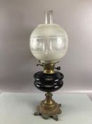 Oil lamp with deep purple central reservoir and etched glass shade and chimney on a brass bass