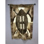 African animal hide wall hanging depicting shield and spears, approx 110cm x 77cm